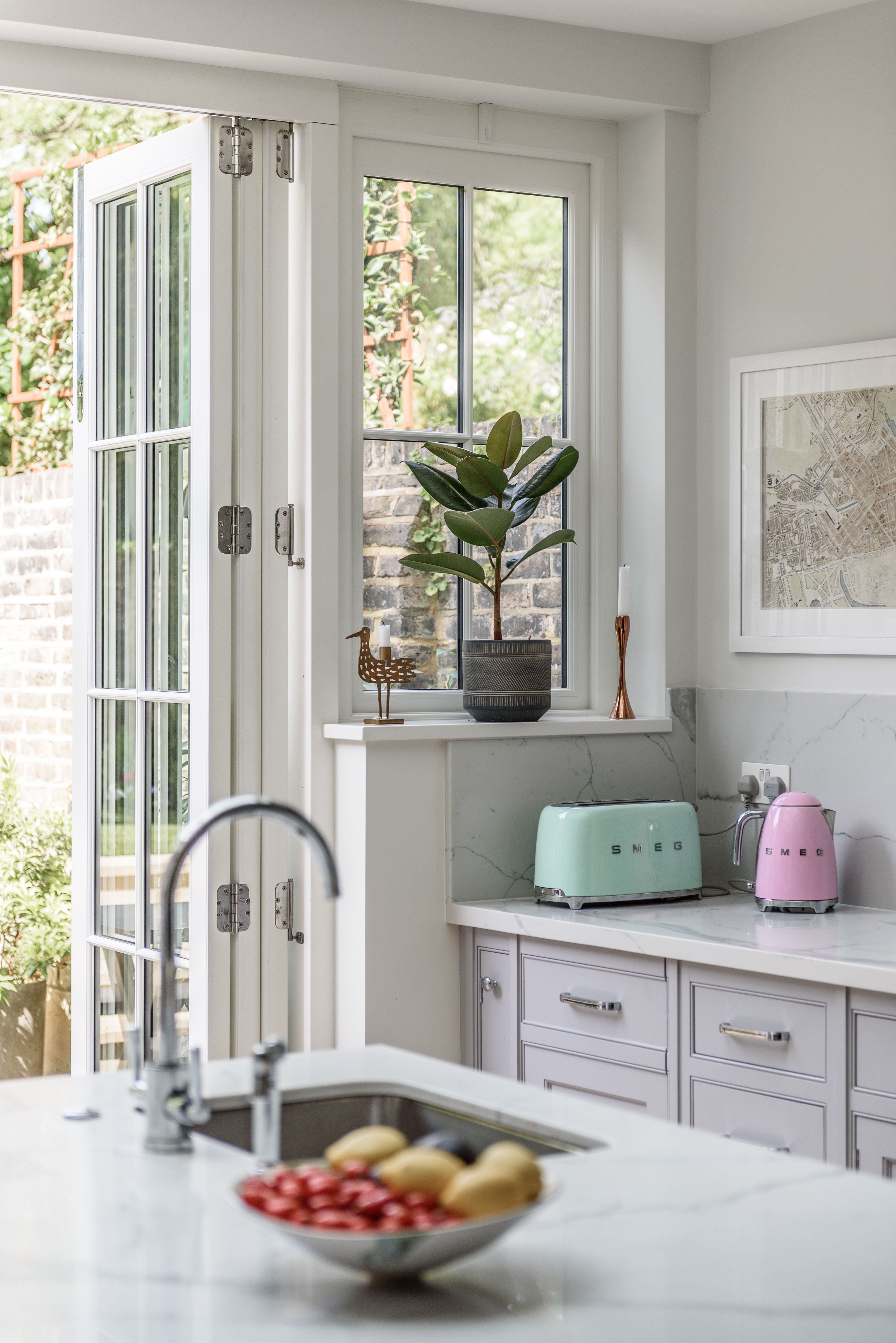 A beautifully designed kitchen with a single flush casement window and classic bi-fold doors, allowing natural light to flood the space.
