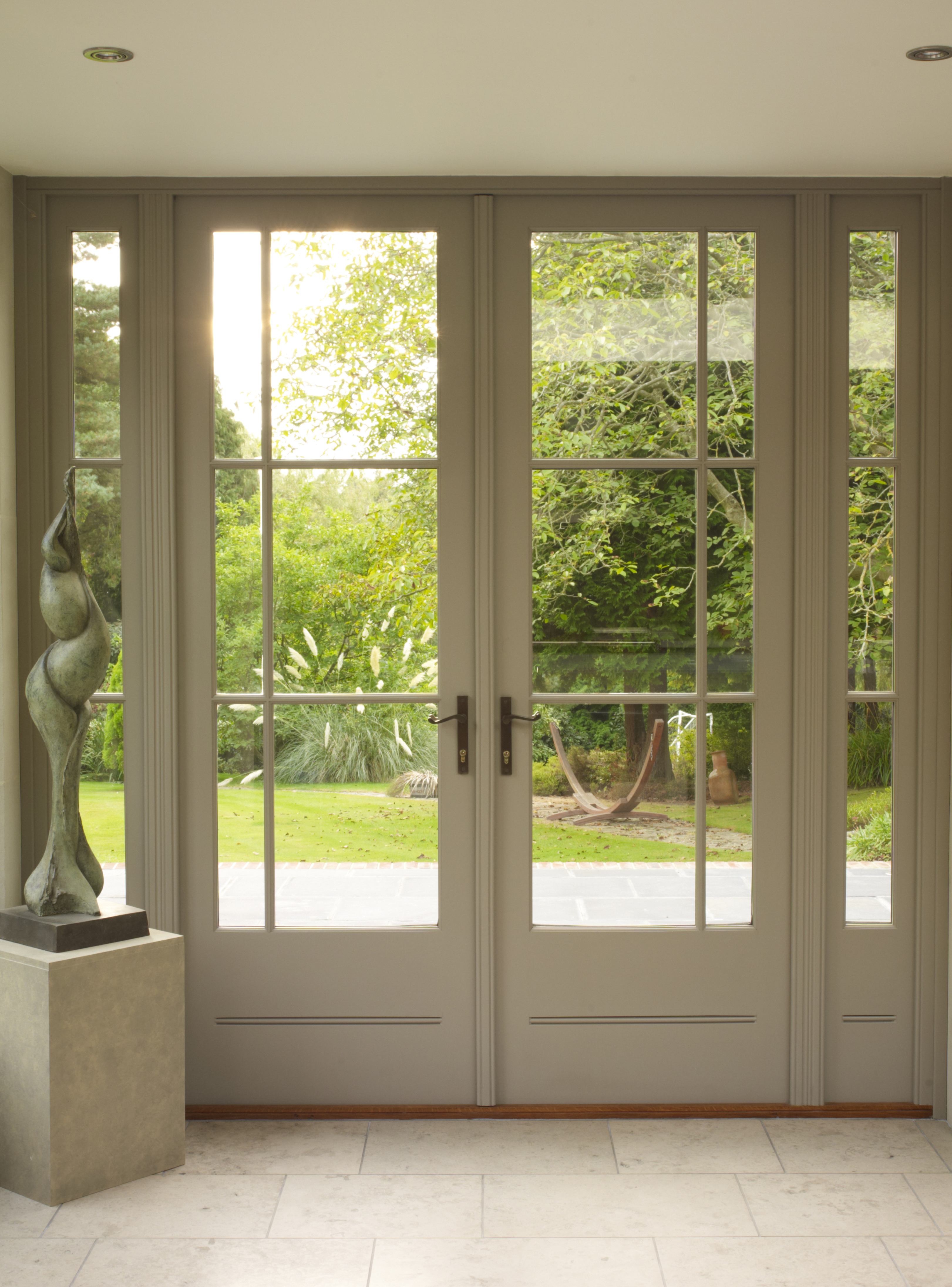 Elegant French doors with side panels, offering a stunning view of the lush garden beyond.
